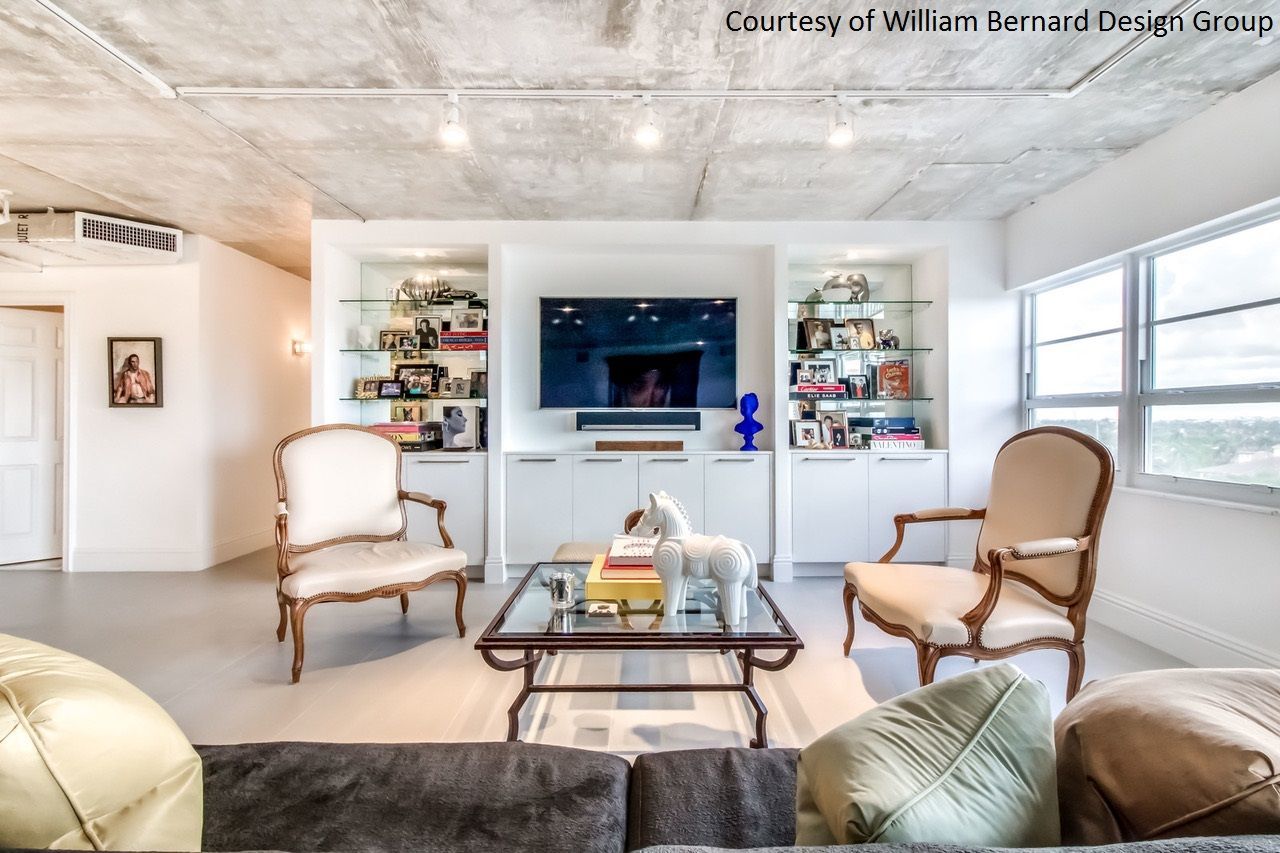 Living room with white built-in shelving, TV, two ornate chairs, glass coffee table, and a grey sofa.
