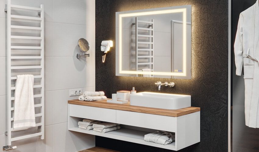 Modern bathroom with illuminated mirror, double sink vanity, white towels, and gray walls