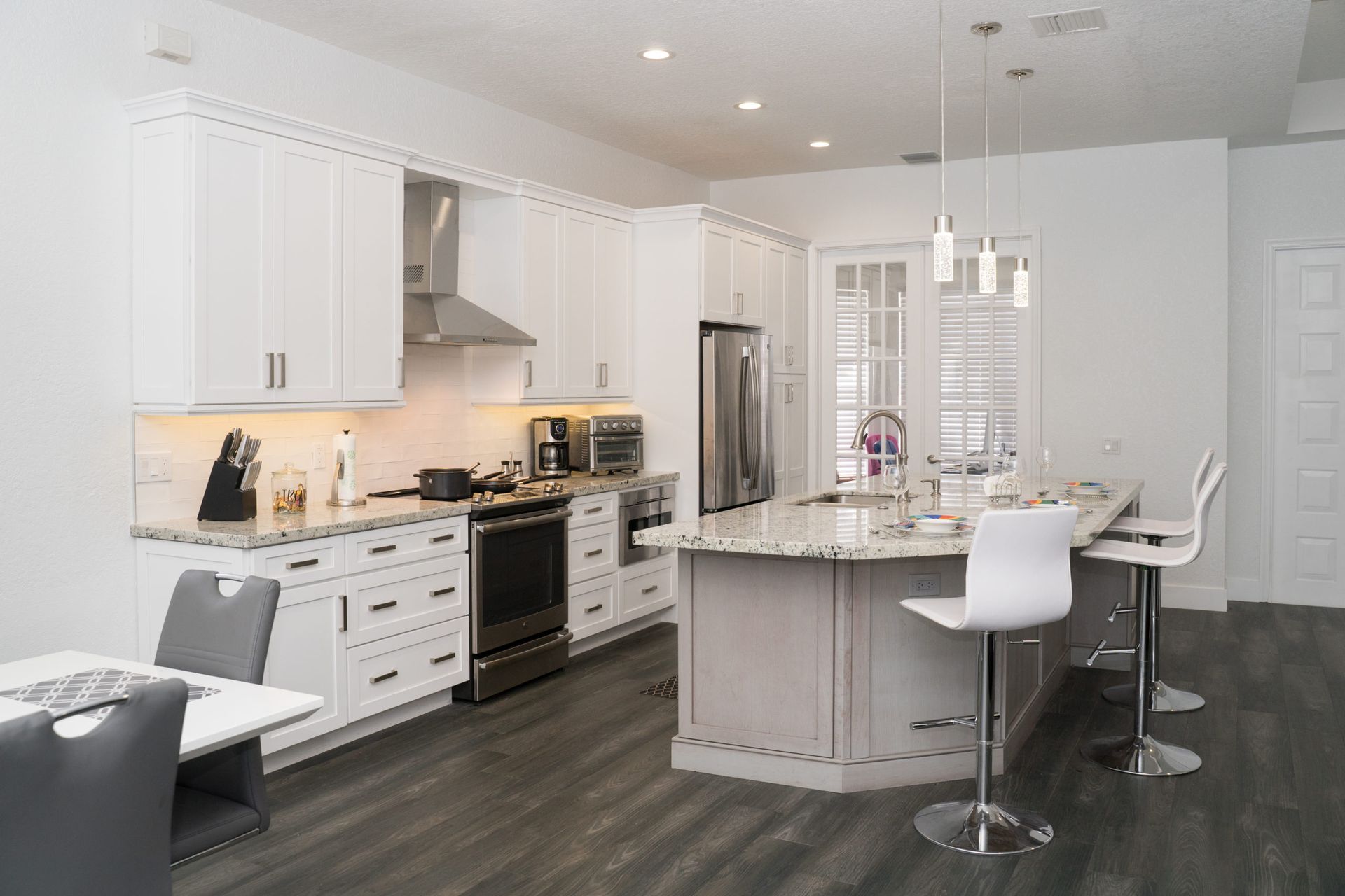 Bright modern kitchen with white cabinets, stainless appliances, and a gray island with bar stools