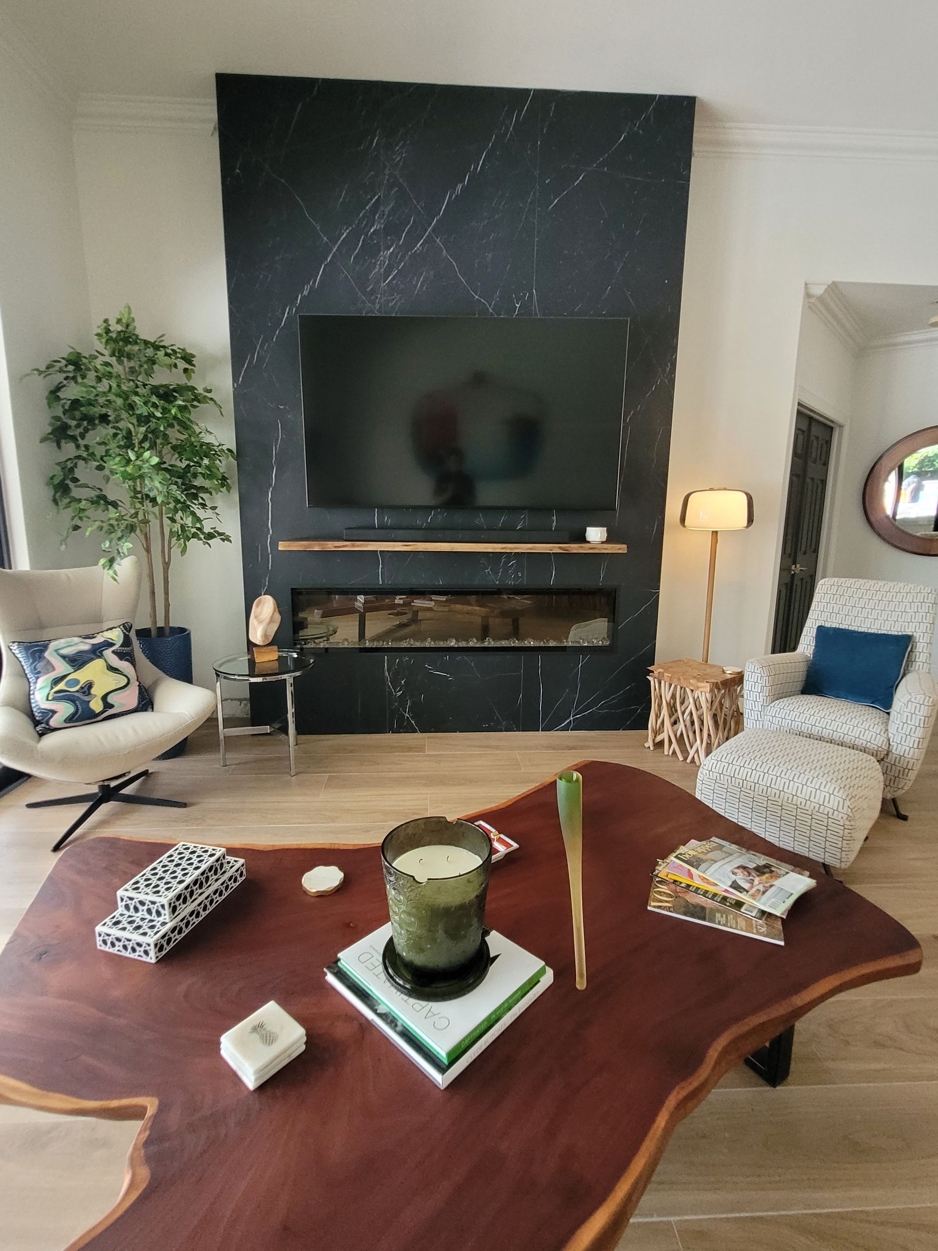 Cozy living room with dark fireplace wall, TV, tan sofas, and wooden coffee table in the foreground