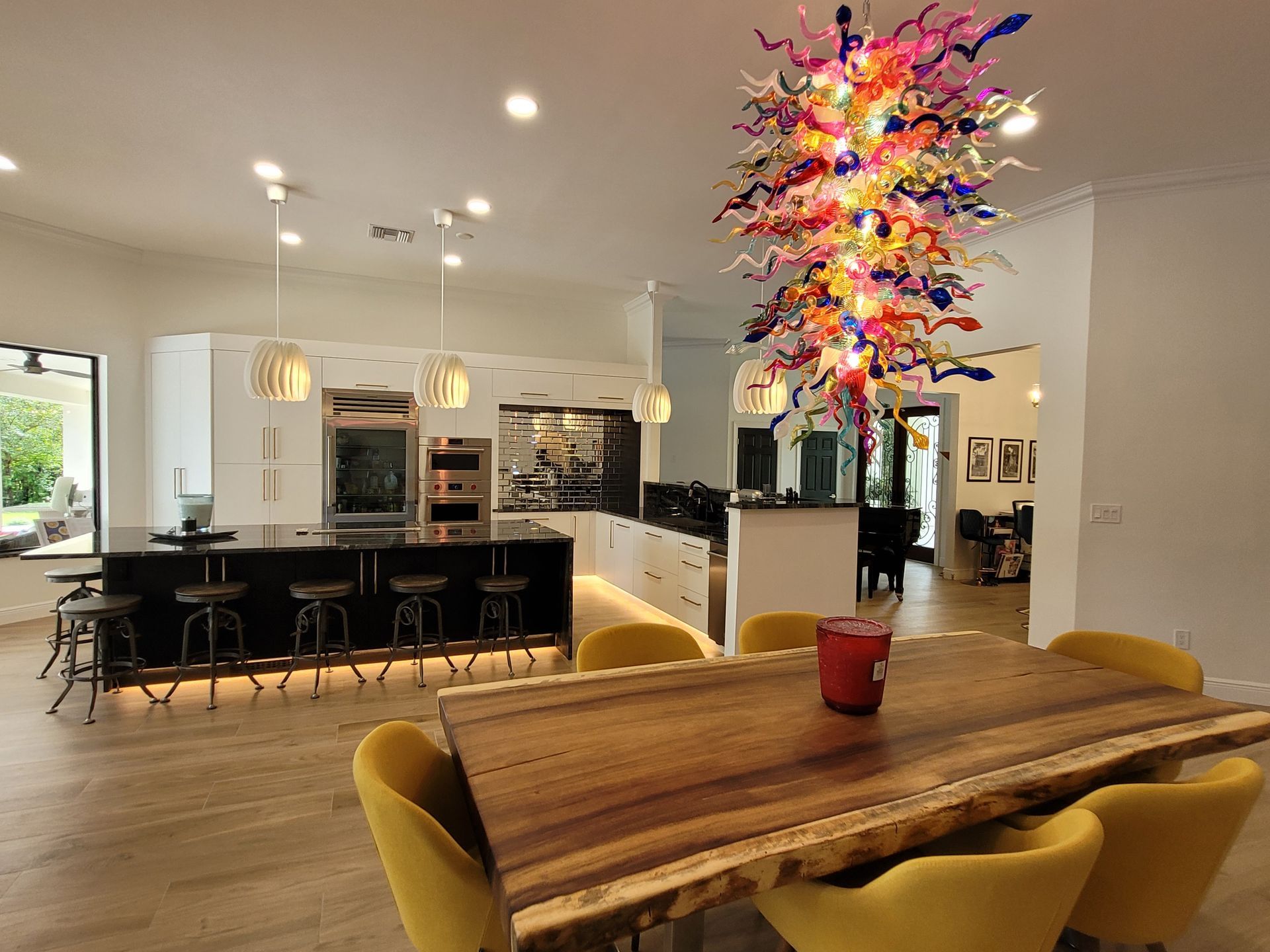 Modern open-concept kitchen and dining area with a colorful hanging light fixture and wooden table