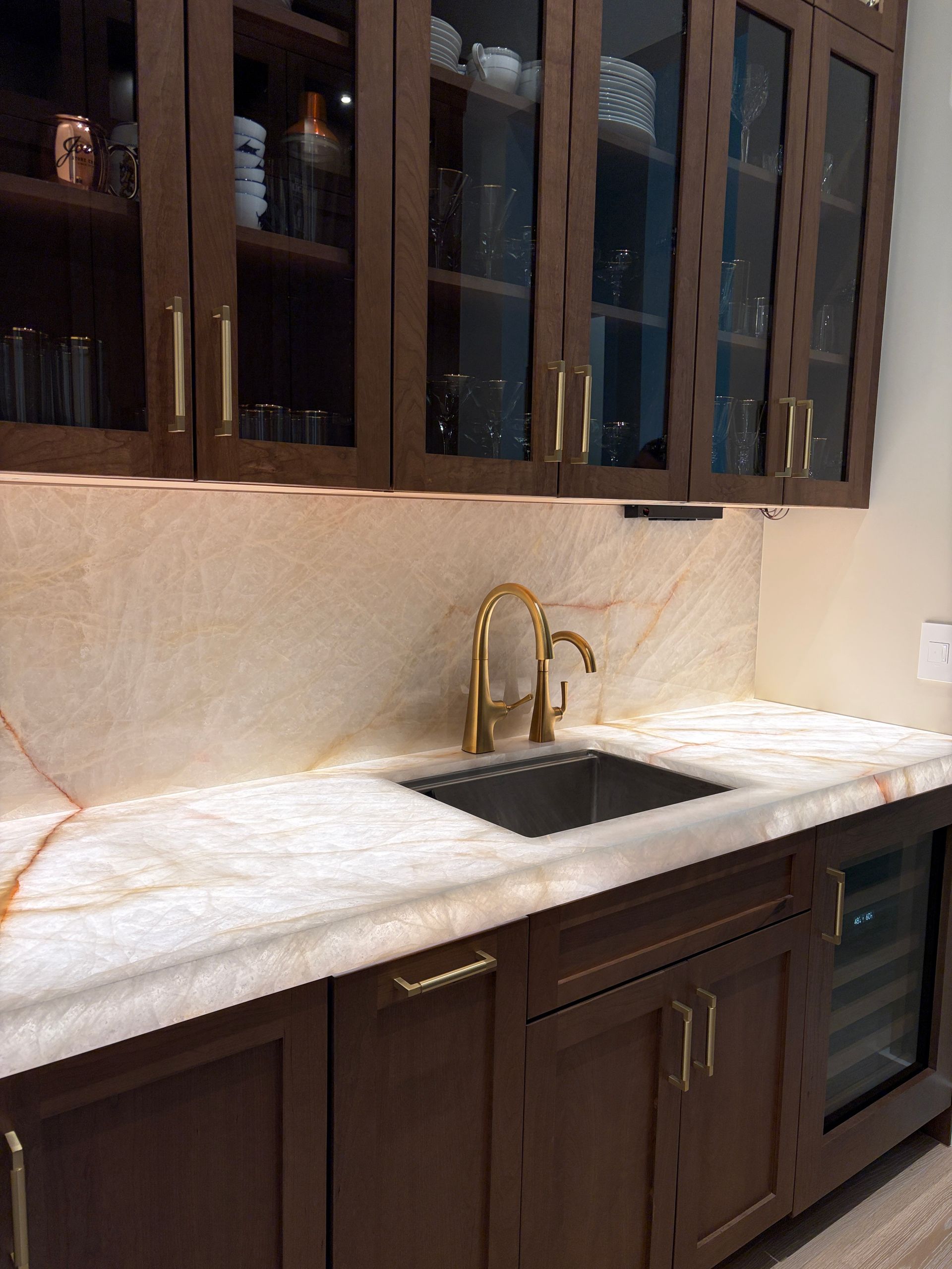 Wet bar with backlit quartzite countertops and glass-front cabinets in Davie FL
