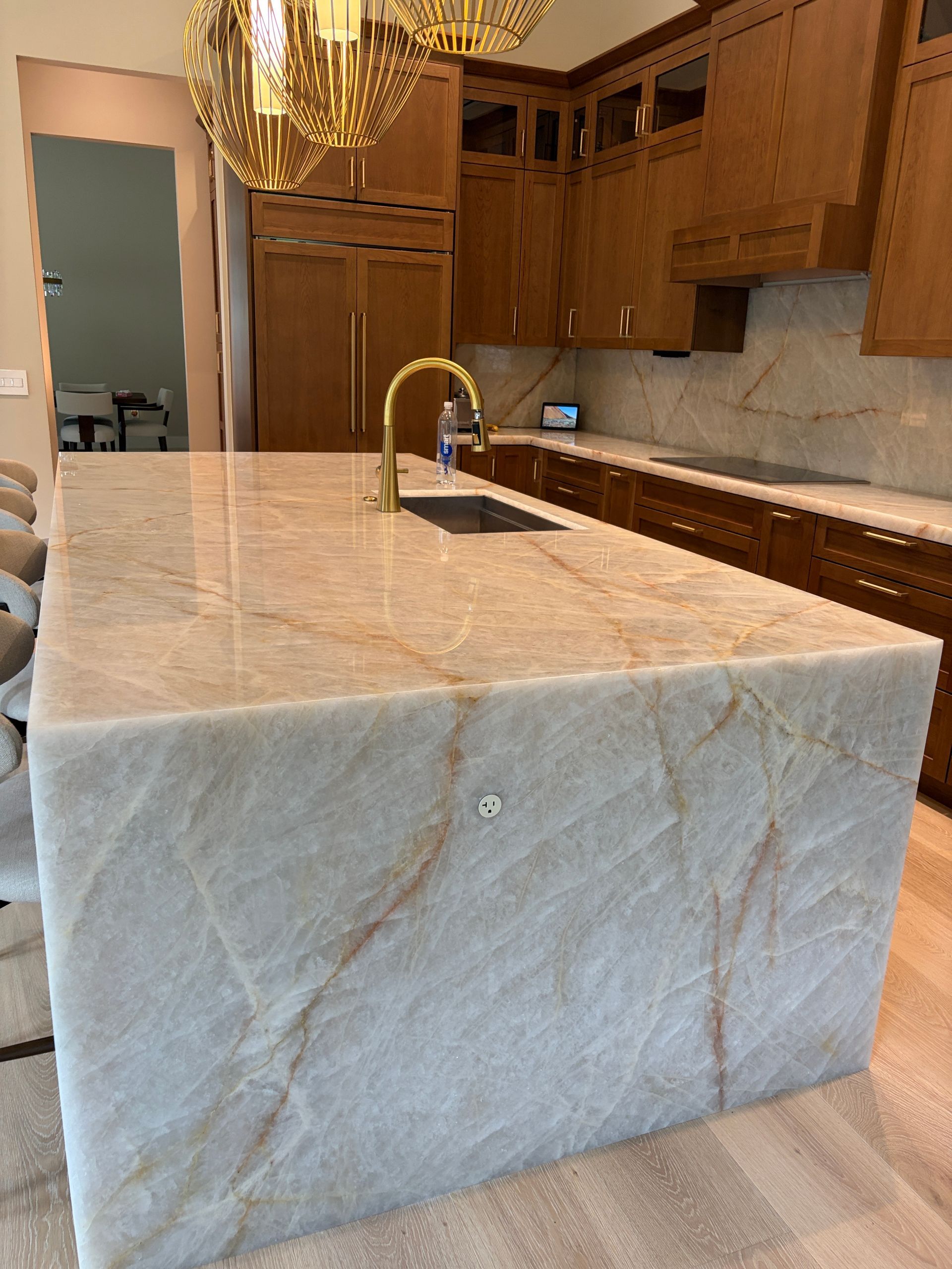 Quartzite waterfall island with brass faucet in a Davie FL kitchen remodel