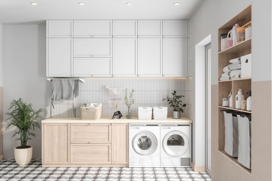 Modern laundry room with white cabinets, light wood counters, front-load washer and dryer, and black-and-white tile floor