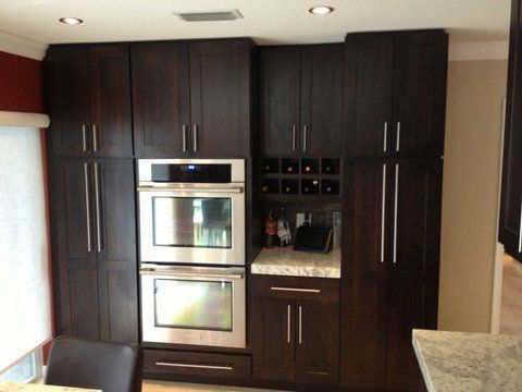 Modern kitchen with dark wood cabinets, built-in stainless steel oven, and granite countertops.