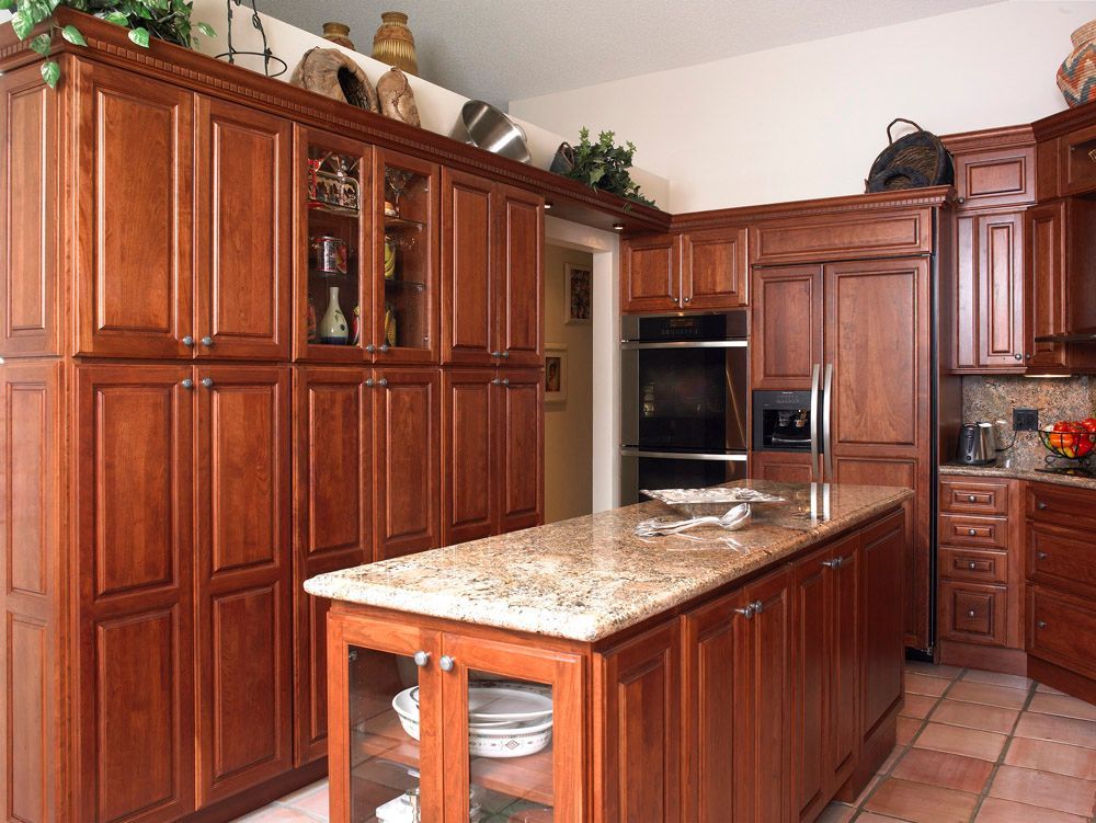 Warm kitchen with rich wood cabinets, granite island, and stainless steel appliances