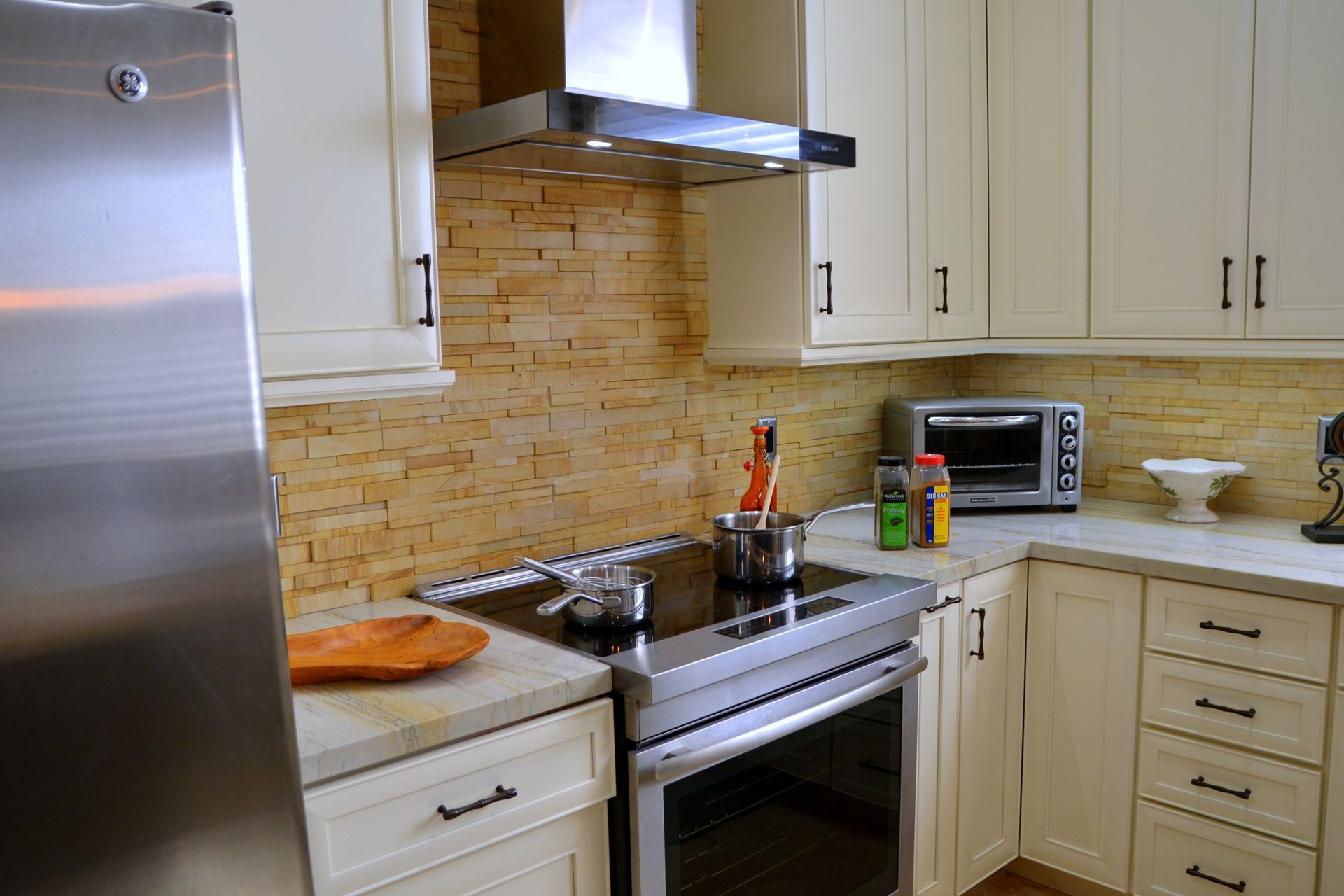 Modern kitchen with stainless steel stove, beige cabinets, and a tiled backsplash