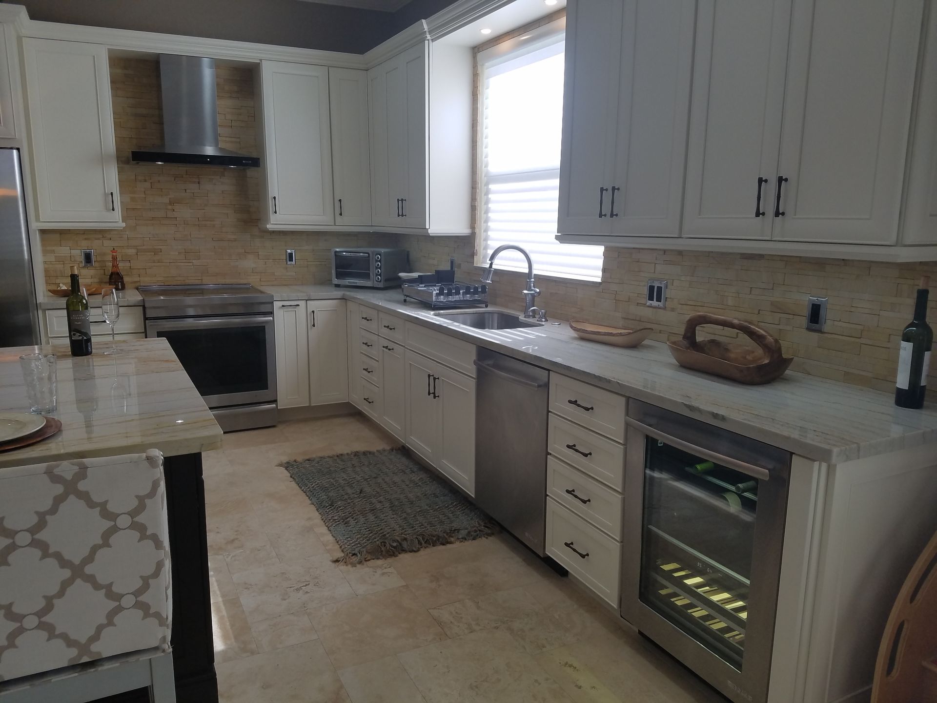 Bright modern kitchen with white cabinets, stainless appliances, and a window over the sink