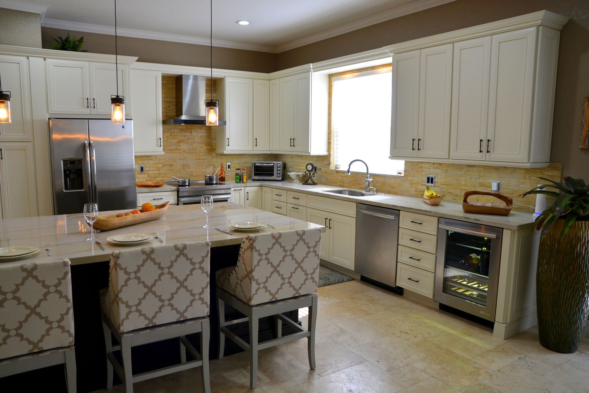 Bright kitchen with white cabinets, granite island, stainless appliances, and a window above the sink