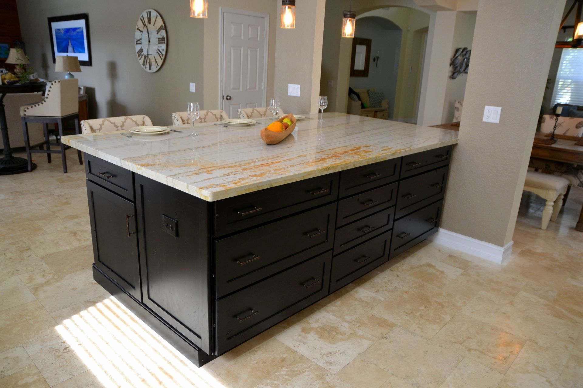 Modern kitchen with a large dark island, light countertops, and beige tile flooring