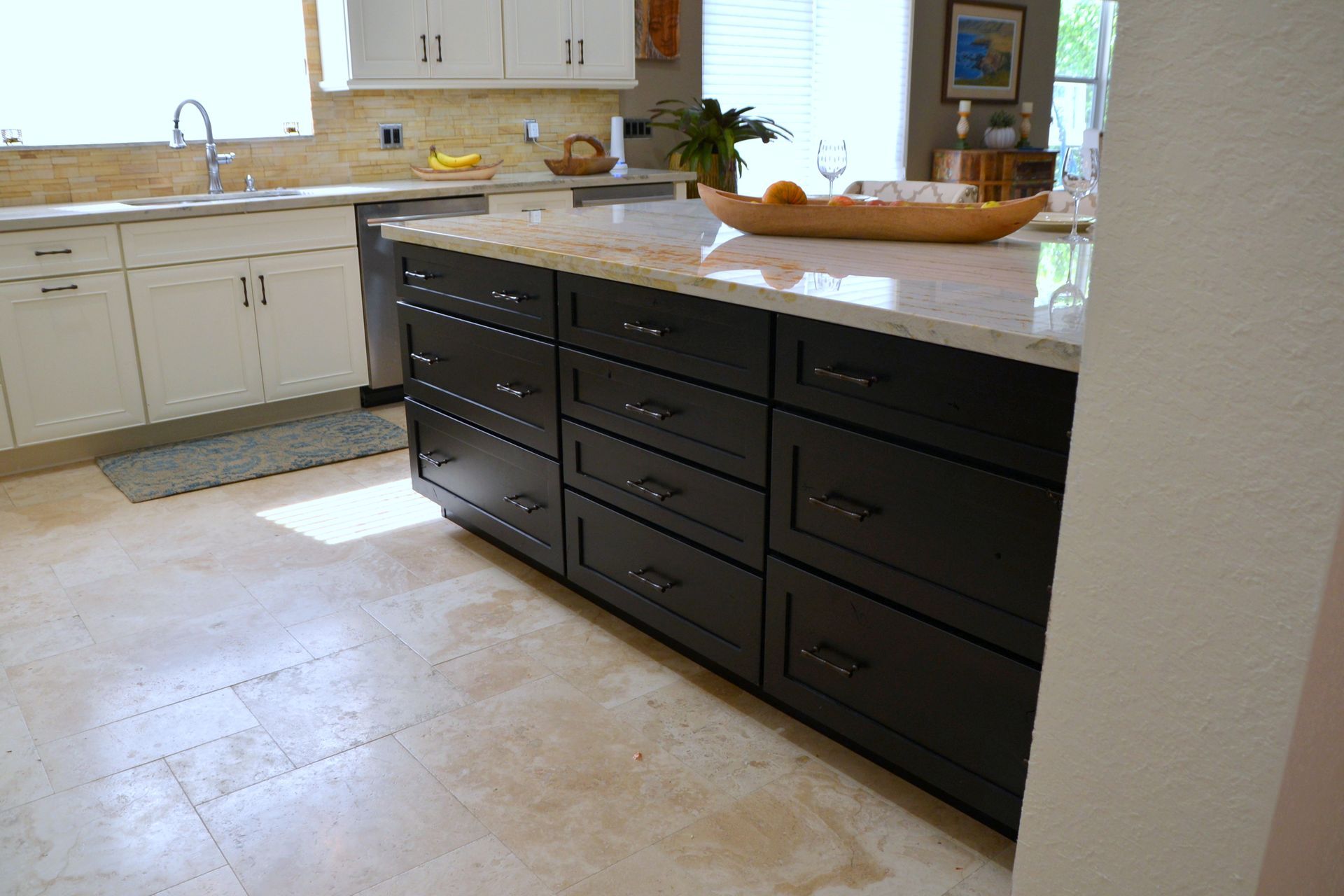 Modern kitchen with dark island cabinets, white countertops, and light tile flooring.