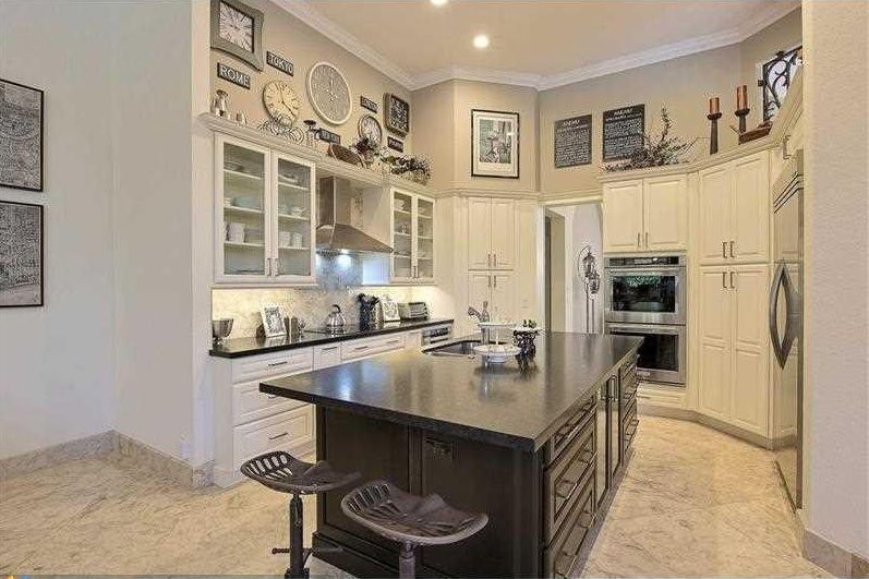 Bright modern kitchen with cream cabinets, large island, and built-in stainless steel appliances.