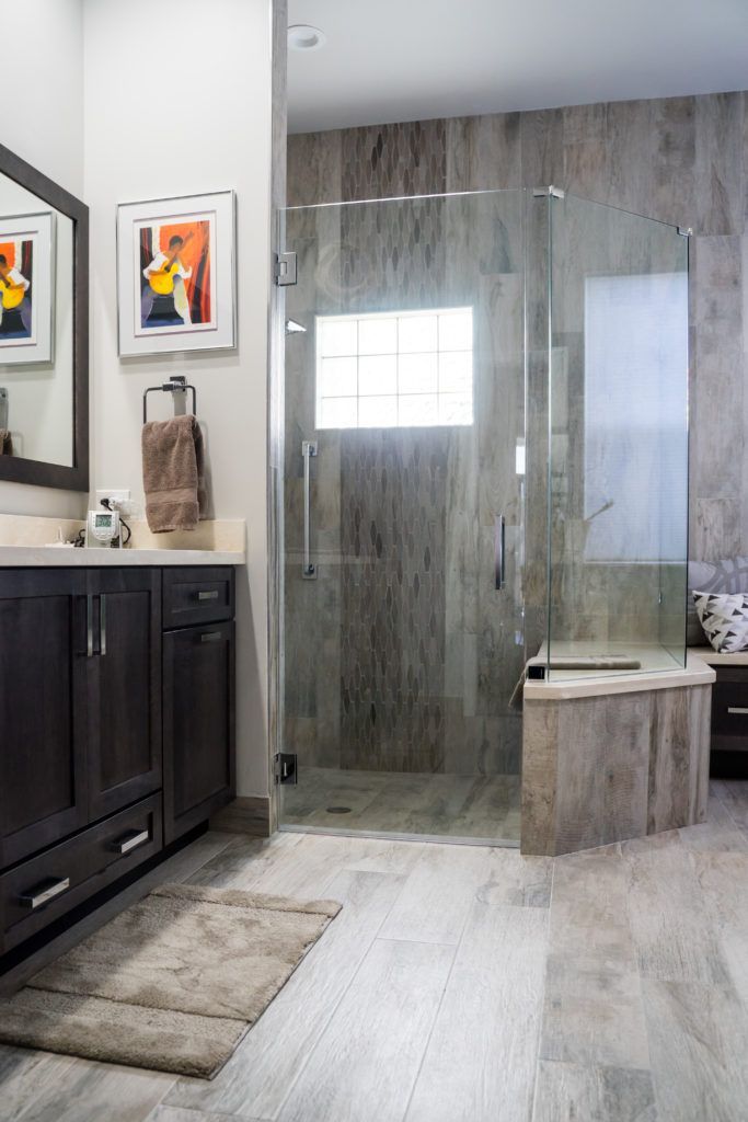 Bathroom with dark wood vanity, glass shower, and gray wood-look flooring.
