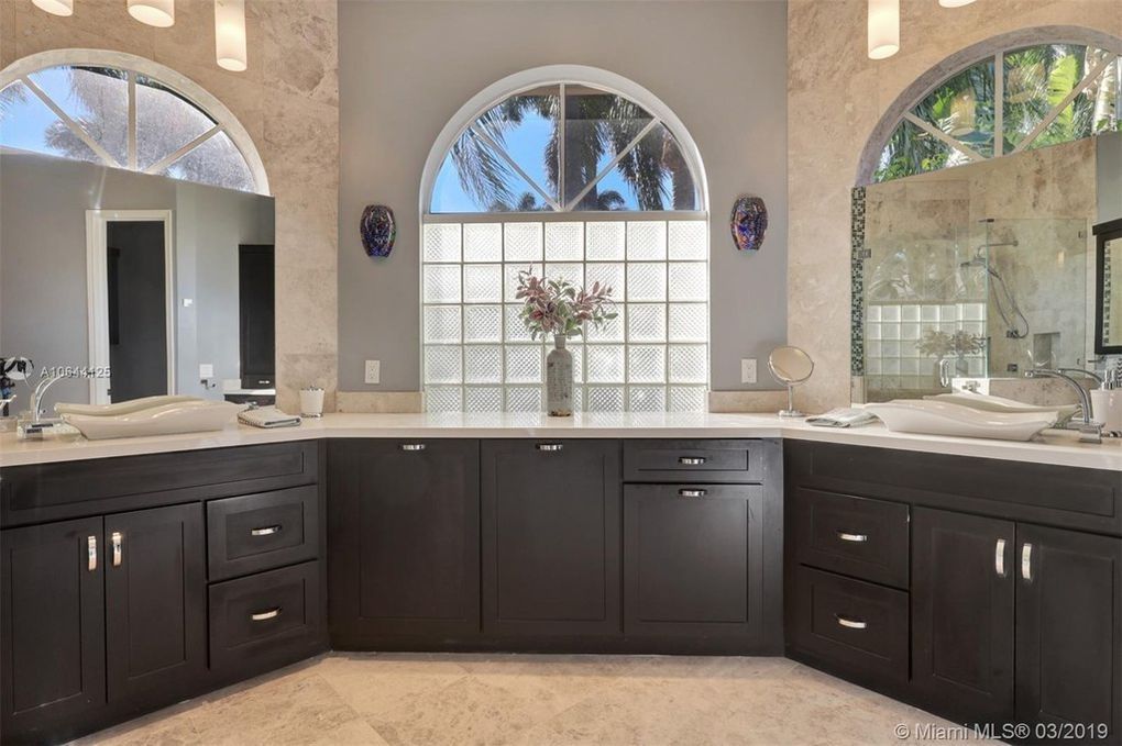 Bathroom with dark brown cabinets, two sinks, and a glass block window.