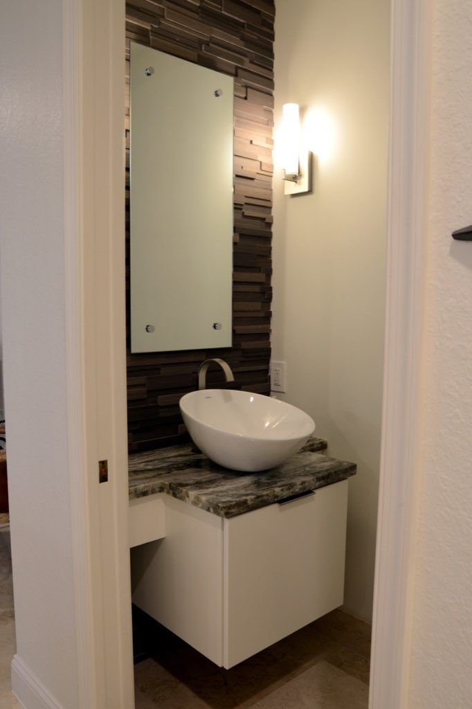 Small powder room with floating vanity, vessel sink, and textured accent wall.