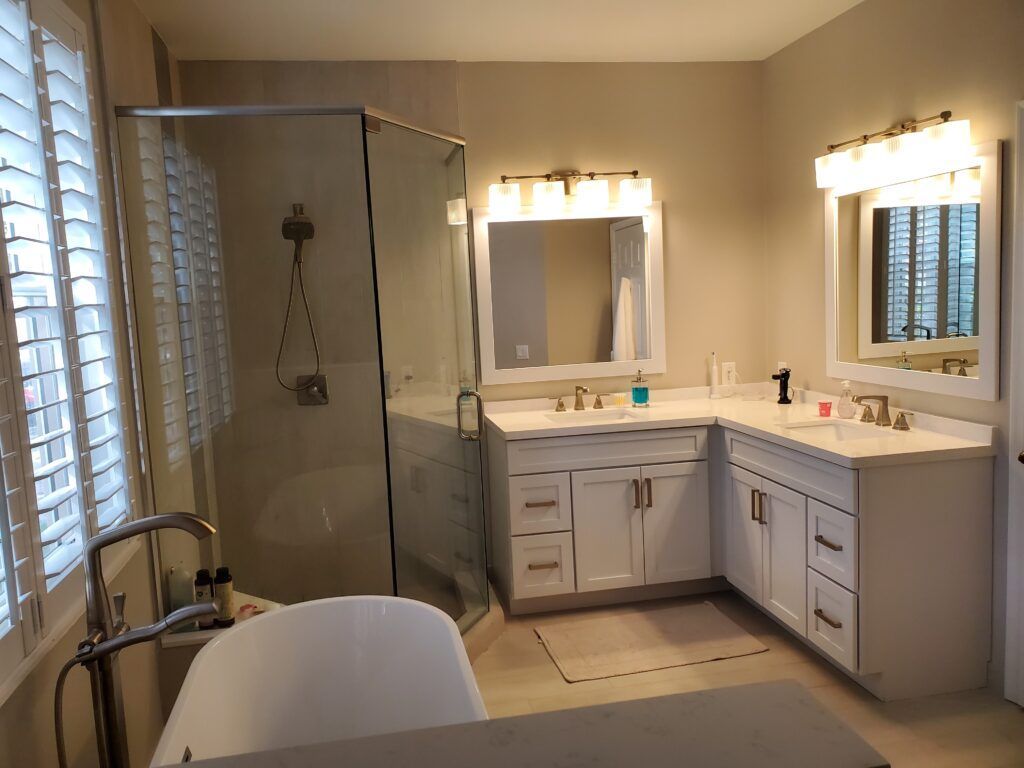 Bathroom with white cabinets, shower, tub, and two sinks with mirrors.
