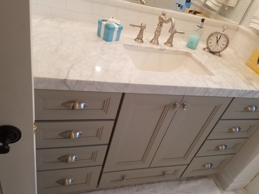 Bathroom vanity with gray cabinets, marble countertop, and silver faucet.