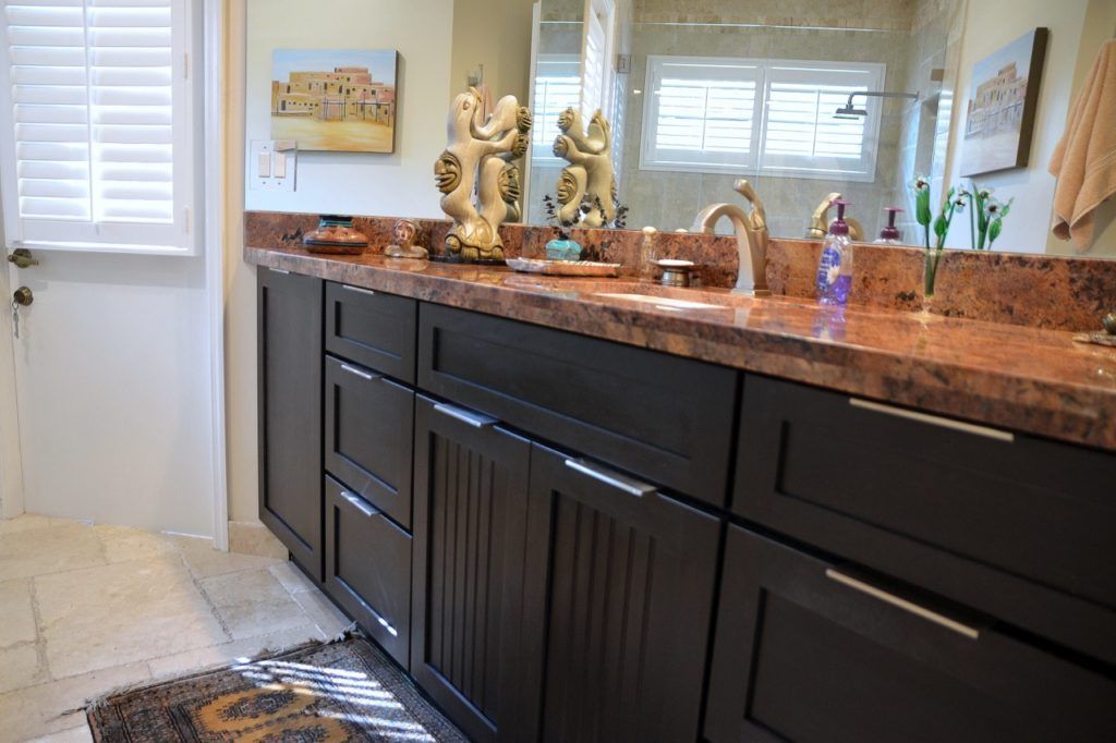 Bathroom with dark brown cabinets, reddish-brown countertop, and decorative items.