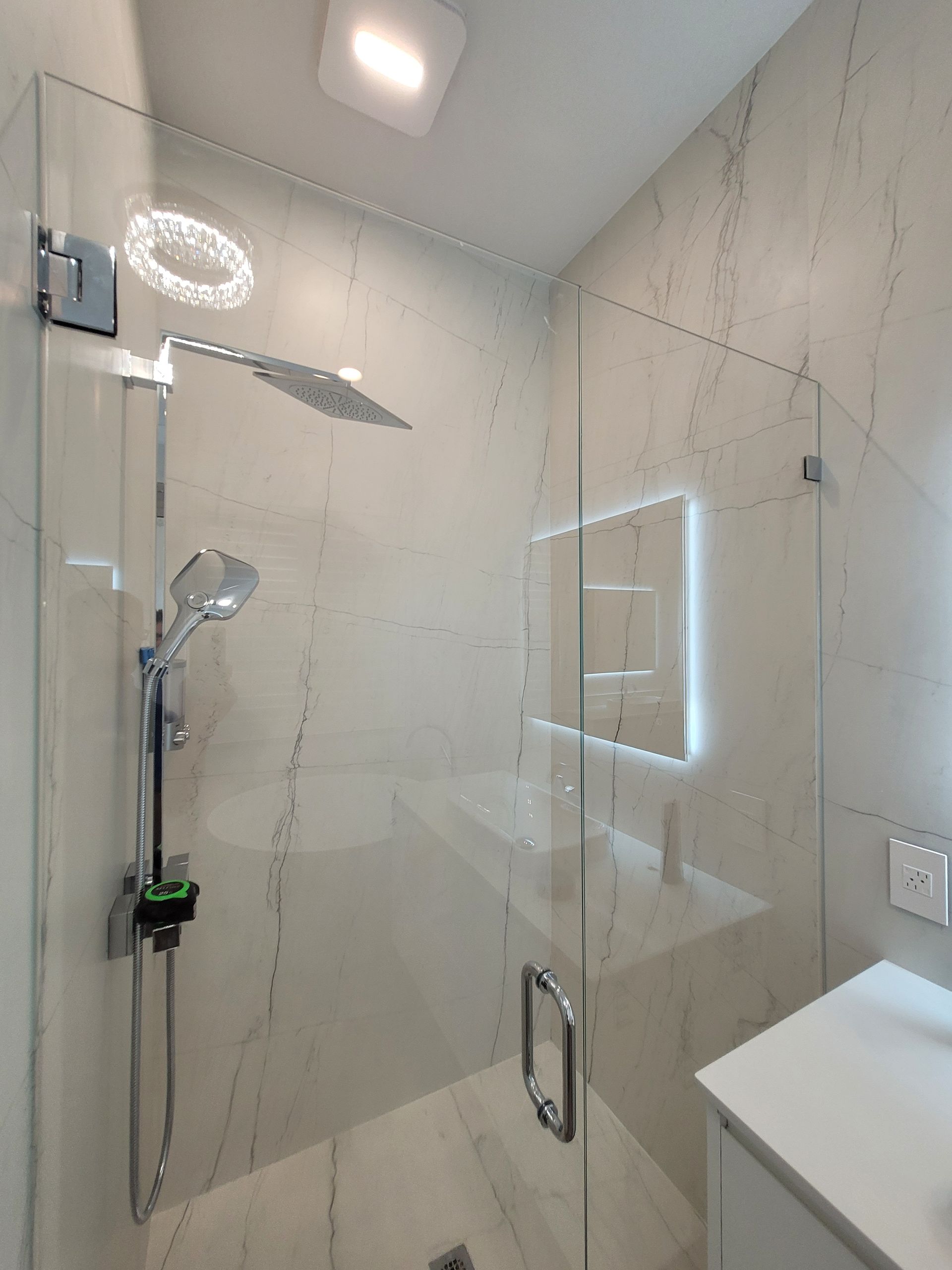 Modern bathroom shower with glass walls and marble tile.
