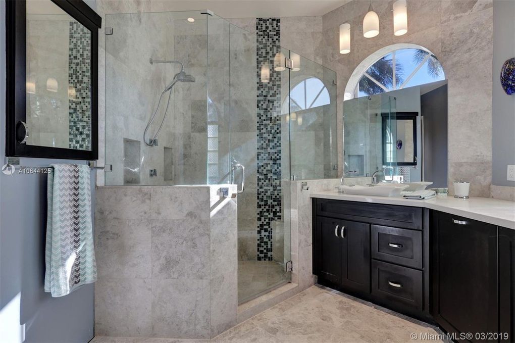 Modern bathroom with walk-in shower, dark wood vanity, glass shower door, and tile.