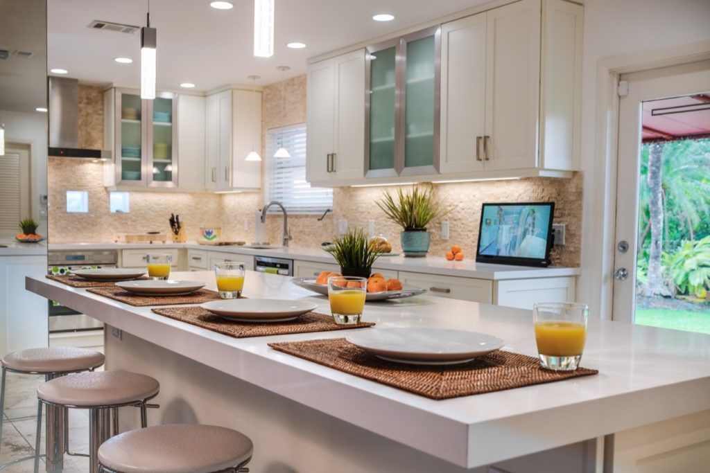 Bright modern kitchen with white cabinets, island seating, and breakfast settings by a window