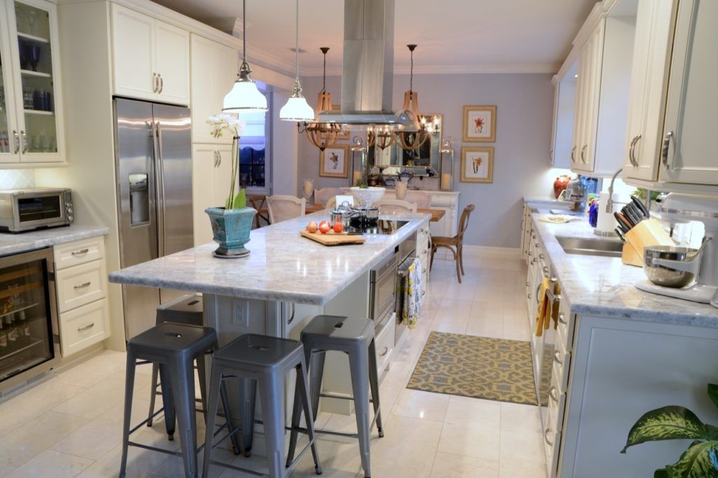 Bright modern kitchen with island, hanging lights, stainless appliances, and a dining area in the background