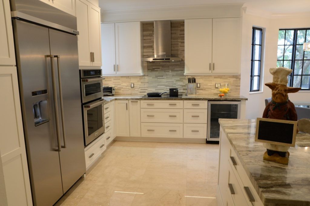 Modern white kitchen with stainless steel appliances and a large island with a decorative vase
