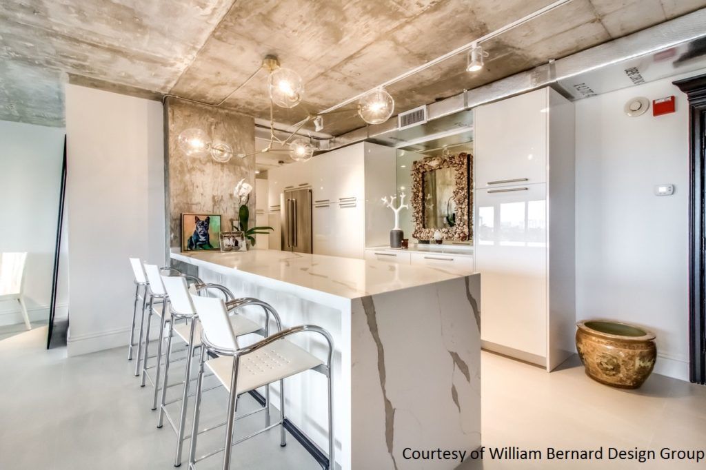 Bright modern kitchen with marble island, white bar stools, and hanging pendant lights