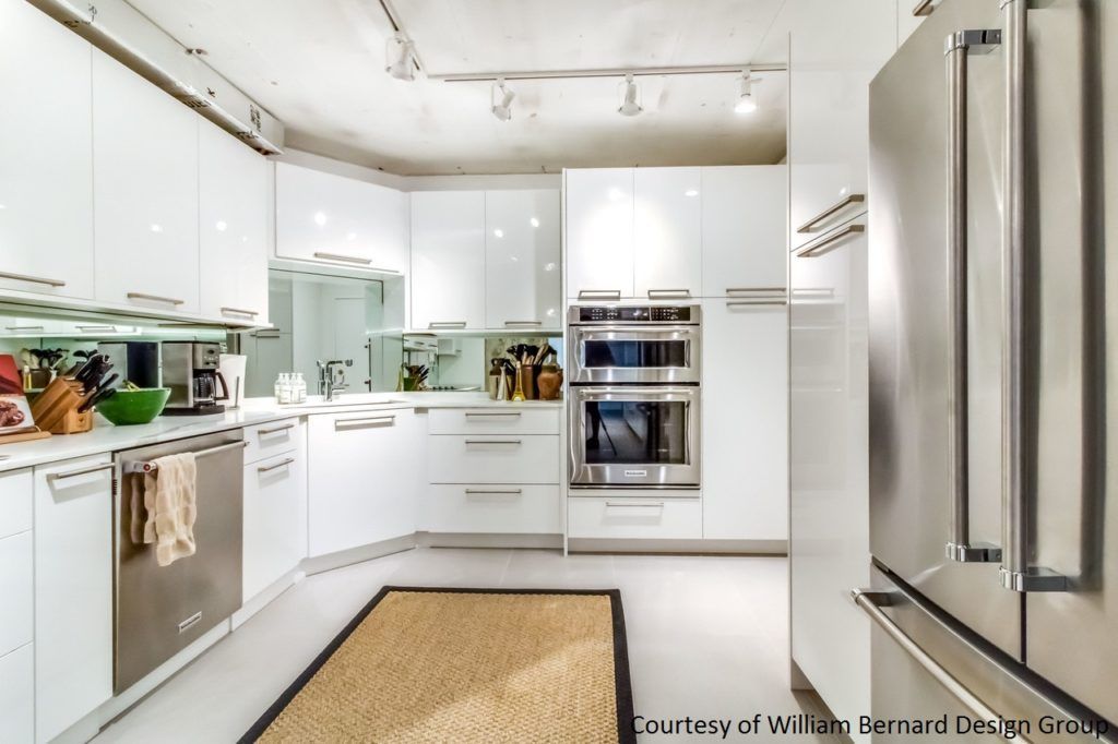 Bright modern kitchen with white cabinets, stainless appliances, and a woven rug on the floor