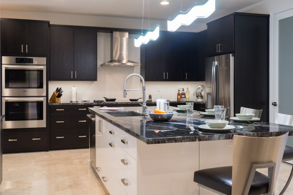 Modern kitchen with dark cabinets, black island, stainless appliances, and pendant lights