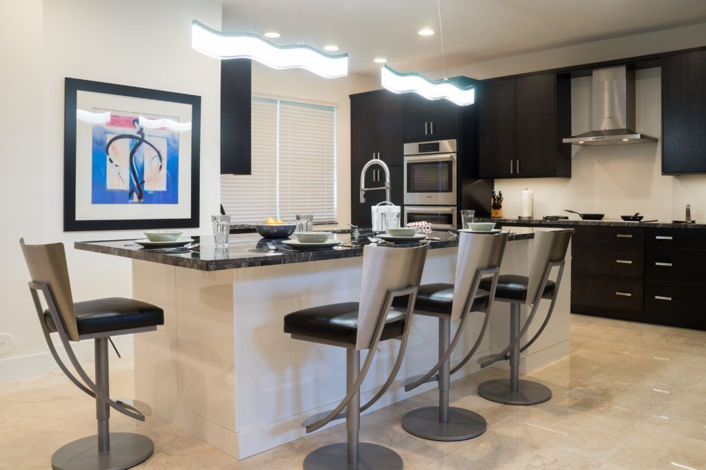 Modern kitchen with island, bar stools, dark cabinets, and a framed abstract painting on the wall