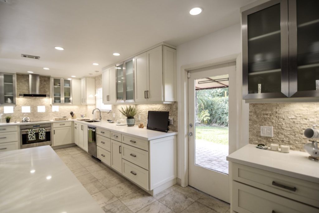 Bright modern kitchen with white cabinets, marble island, and stainless steel appliances