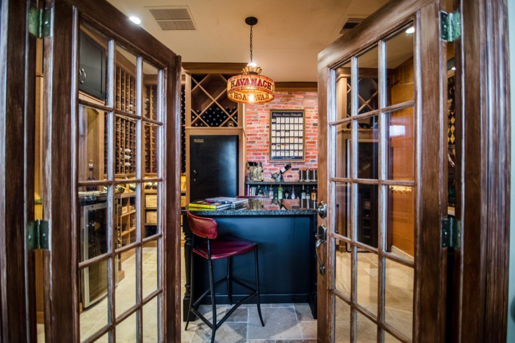 Bar with glass doors, red stools, and warm pendant lighting in a narrow hallway.