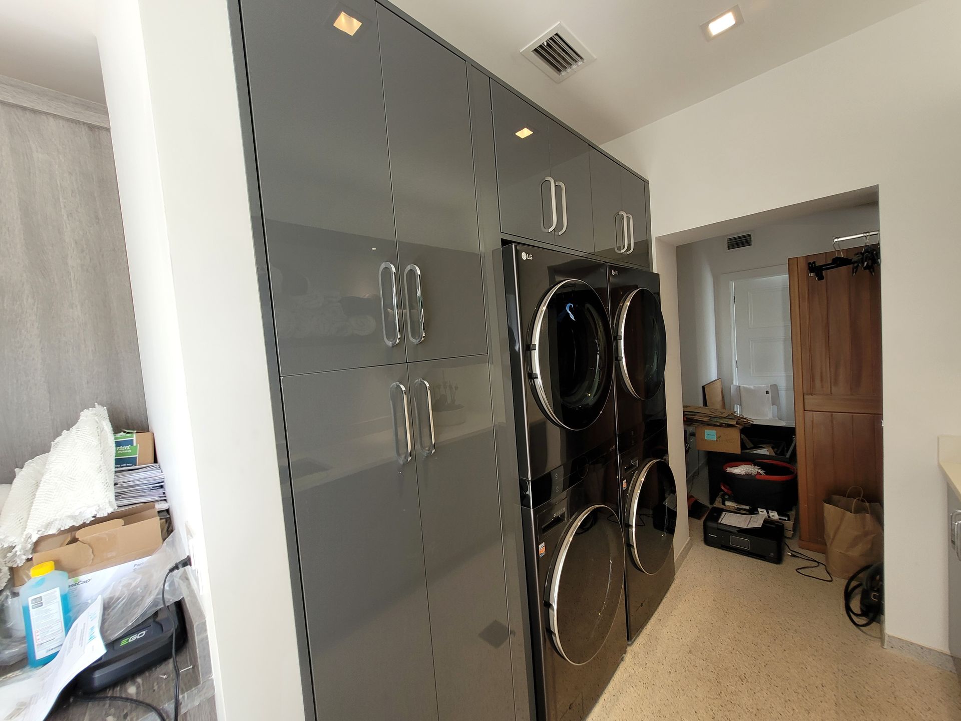 Laundry room with gray cabinets and stacked washer-dryers next to a doorway