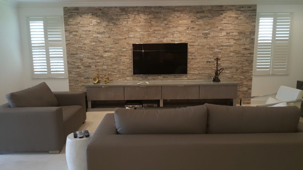 Modern living room with stone fireplace, wall-mounted TV, and gray sofas