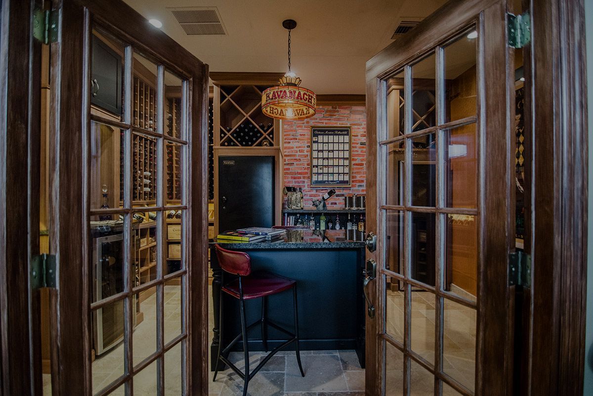 Wood-paneled bar alcove with open glass doors, a dark counter, stools, and a hanging mosaic lamp.