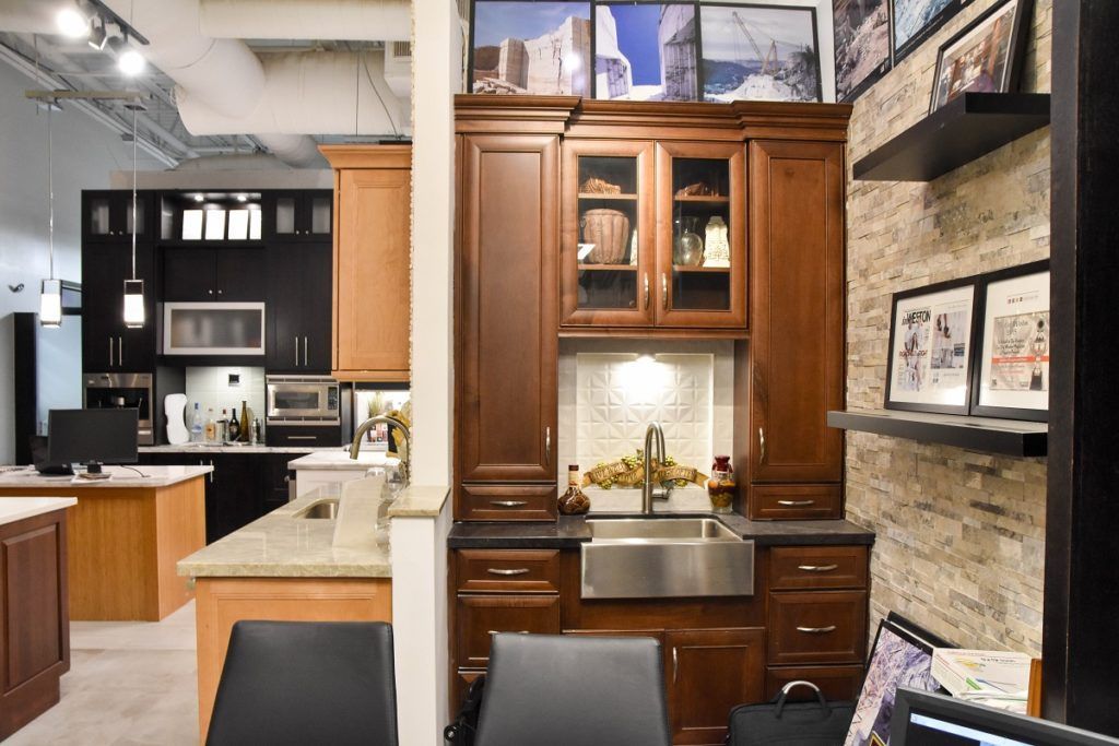 Modern kitchen showroom with dark wood cabinets, a stainless sink, and stone accents