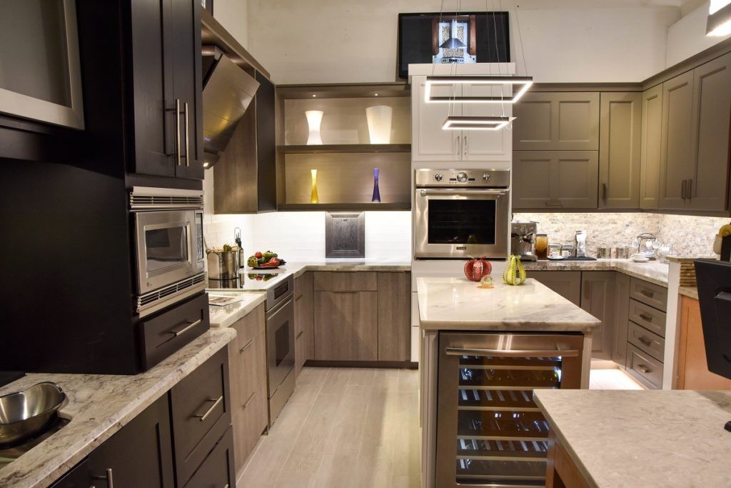 Modern kitchen with dark wood cabinets, white countertops, stainless appliances, and a central island with wine storage