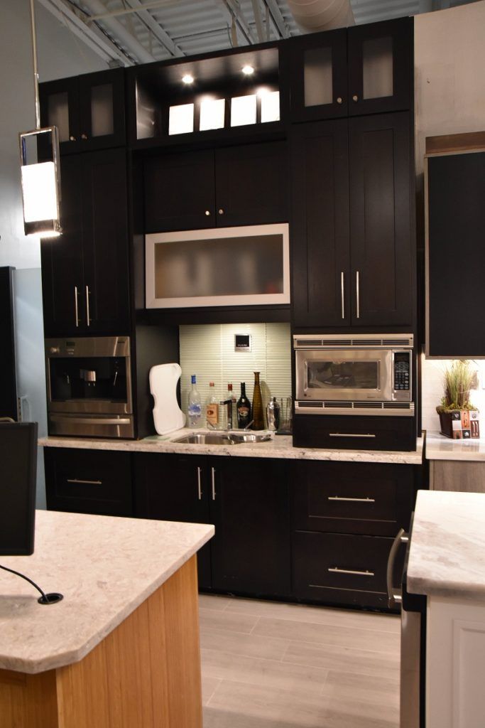 Modern dark kitchen with black cabinets, built-in appliances, and light countertops