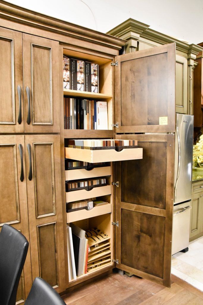 Wooden cabinet with a pull-out storage organizer and shelves, displayed open in a showroom.