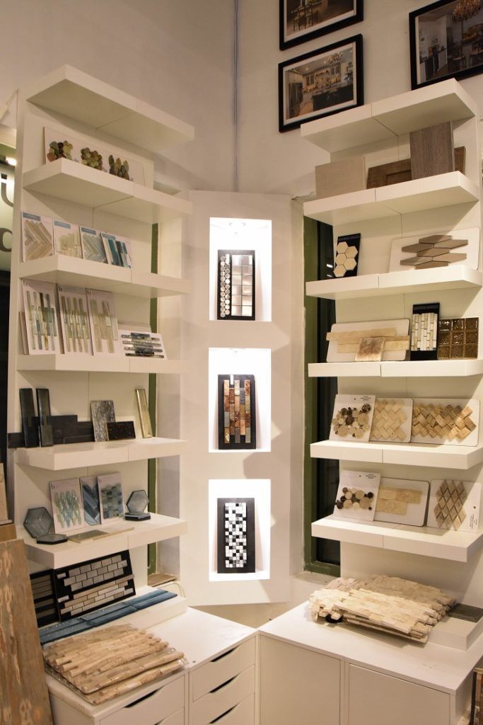 Small white room with built-in shelves displaying books and baskets, lit by three narrow wall windows.