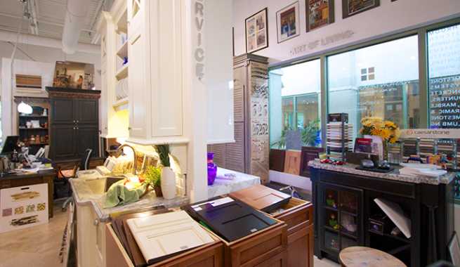 Bright kitchen with white cabinets, wooden island, and black countertops beside a sunlit window.