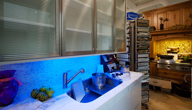 Modern kitchen with blue-lit backsplash, stainless sink, and wooden cabinetry