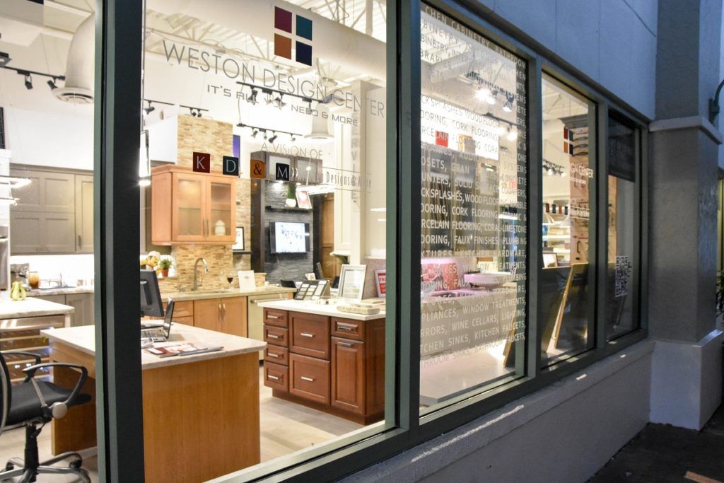 Storefront window display with wooden cabinets and furniture lit inside a shop at dusk