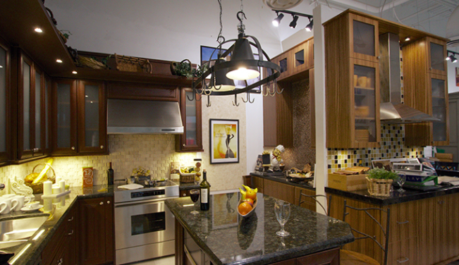 Modern kitchen with dark wood cabinets, granite island, pendant lights, and fruit on the counter