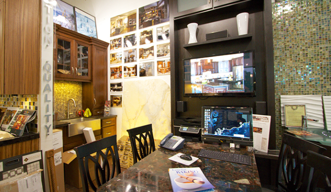 Cluttered office with wall photos, computer monitors, desk, and wooden cabinet under warm lighting