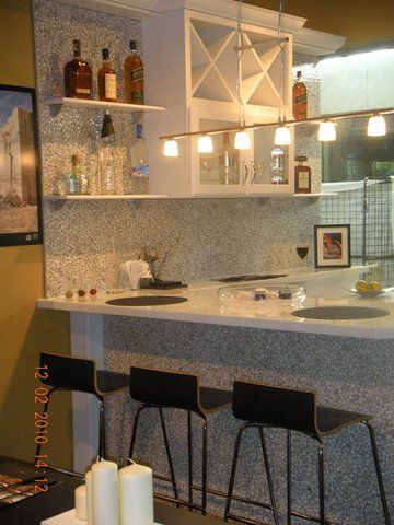 Modern kitchen bar with white shelves, pendant lights, and three black stools