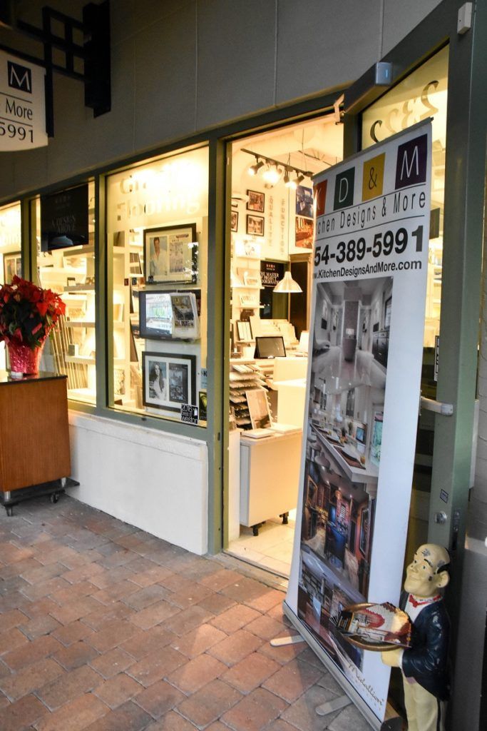 Storefront entrance with lit display windows, open door, and a sidewalk sign outside