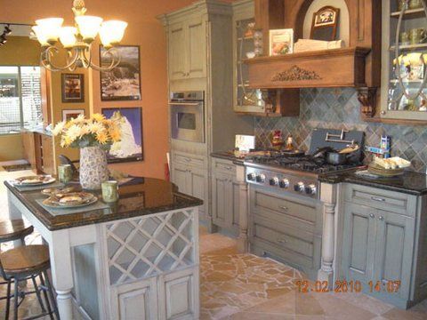 Modern kitchen with island, gray cabinets, tiled floor, stove, and hanging light fixture