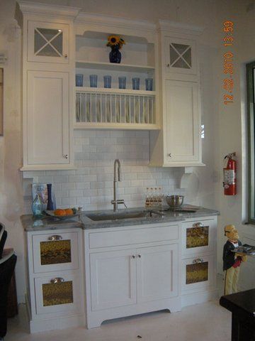 White kitchen hutch with sink, cabinets, open shelves, and decorative items against a tiled wall